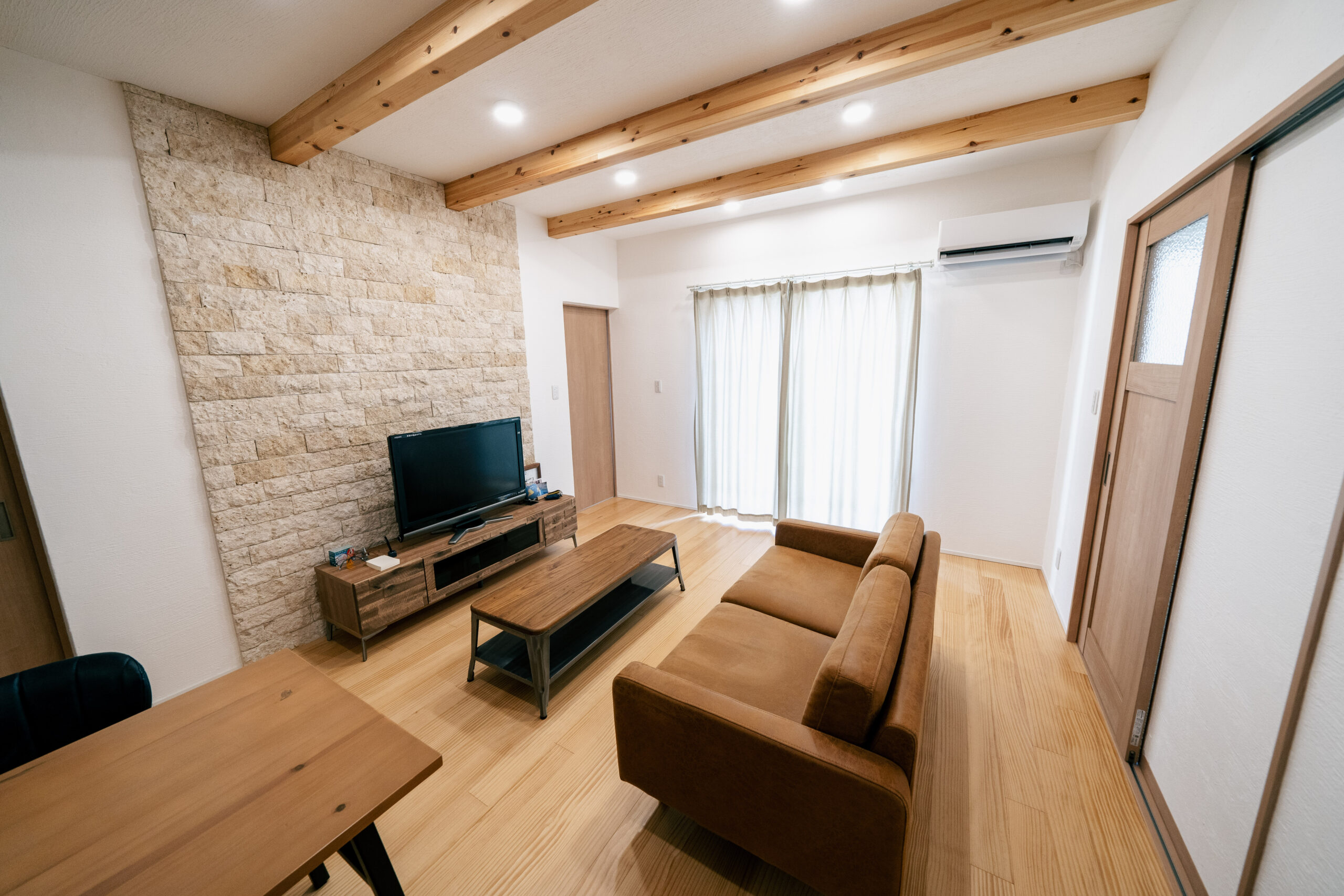 梁の見える天井と石貼りの壁が、温もりと上質さを両立させる印象的な空間。